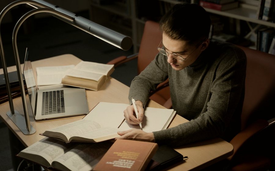 Un étudiant travaillant à son bureau, sous une lampe.
