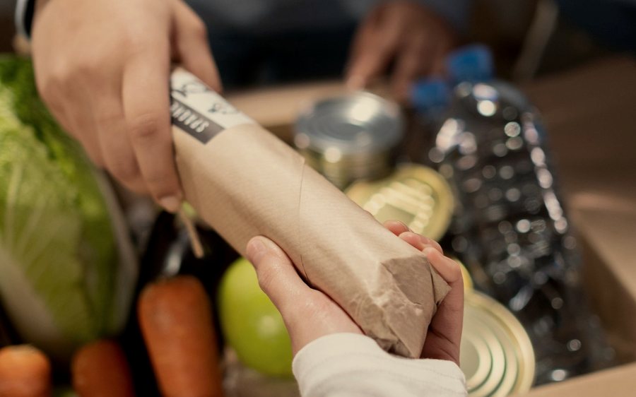 Des mains rangeant des denrées dans un carton de collecte.