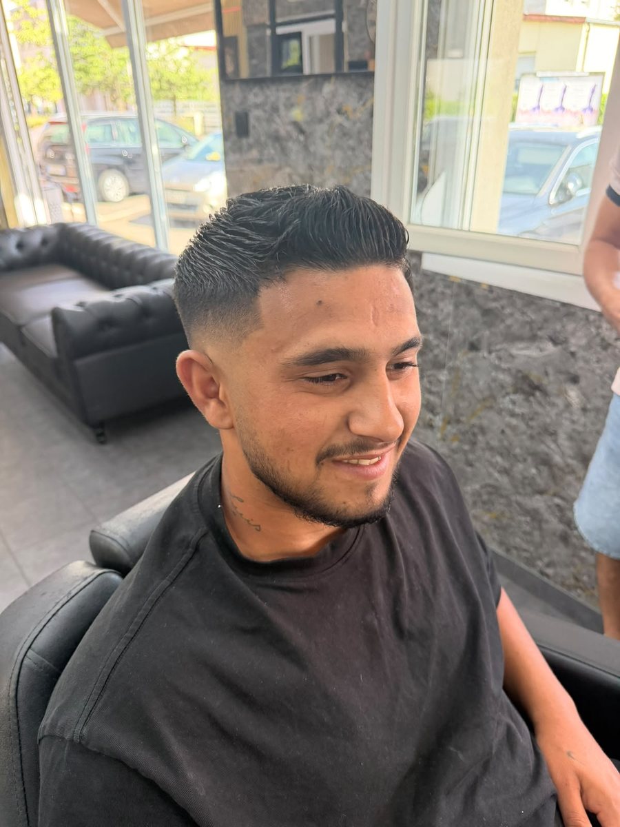 Un homme souriant après la coupe de cheveux qui lui a été offerte.